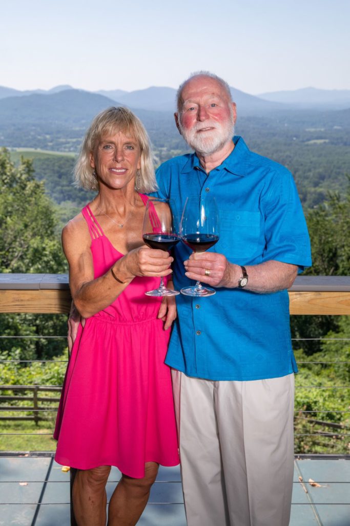 Couple Standing in Front of Mountains Clicking Wine Glasses